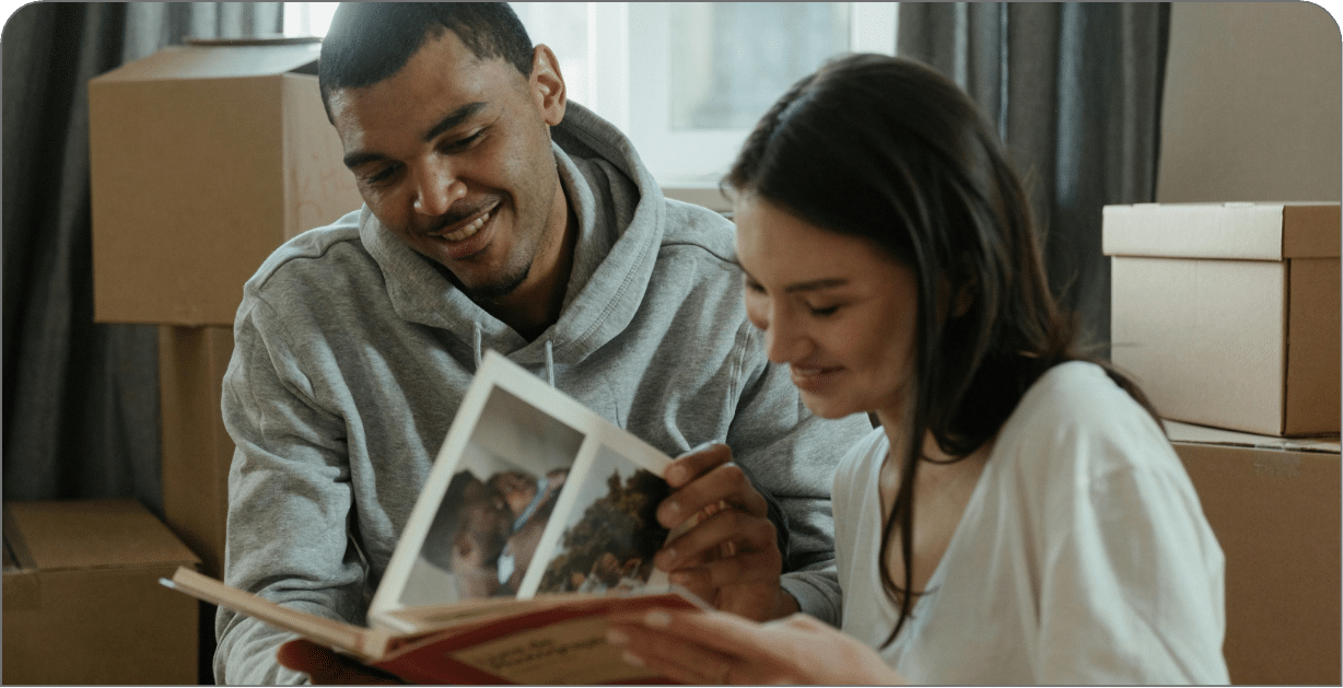 Happy tenants looking at photo album while unpacking.